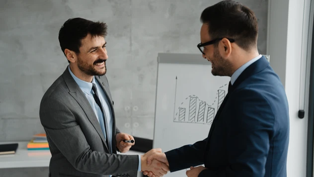 Kunde og rådgiver i håndtrykk foran diagram – et uttrykk for tillit, oppfølging og resultater over tid ved firmareiser fra et reisebyrå for bedrifter. Kunde og rådgiver i håndtrykk foran diagram – et uttrykk for tillit, oppfølging og resultater over tid ved firmareiser fra et reisebyrå for bedrifter.