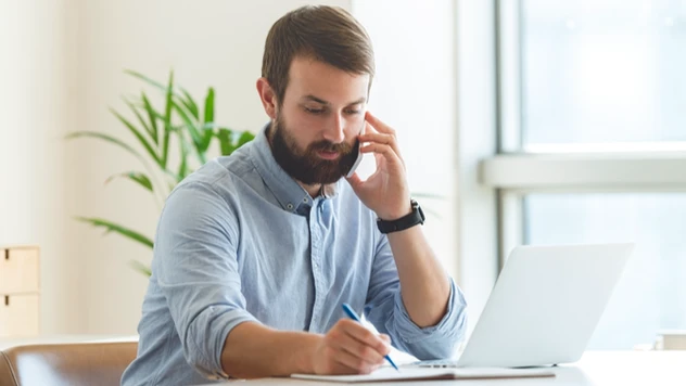 Rådgiver i telefon mens han noterer – et uttrykk for tilgjengelighet og handling når det virkelig haster ved firmareiser fra et reisebyrå for bedrifter. Rådgiver i telefon mens han noterer – et uttrykk for tilgjengelighet og handling når det virkelig haster ved firmareiser fra et reisebyrå for bedrifter.